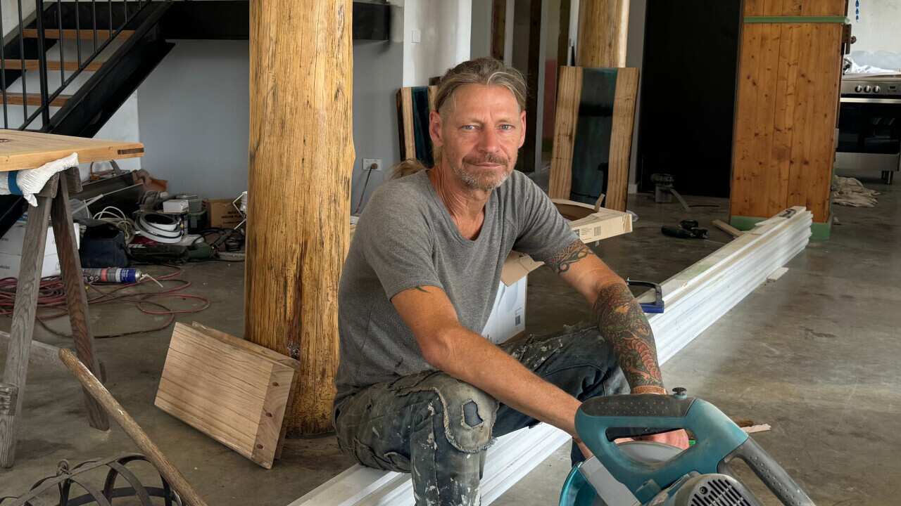 A man sitting on the floor in his under-construction home.