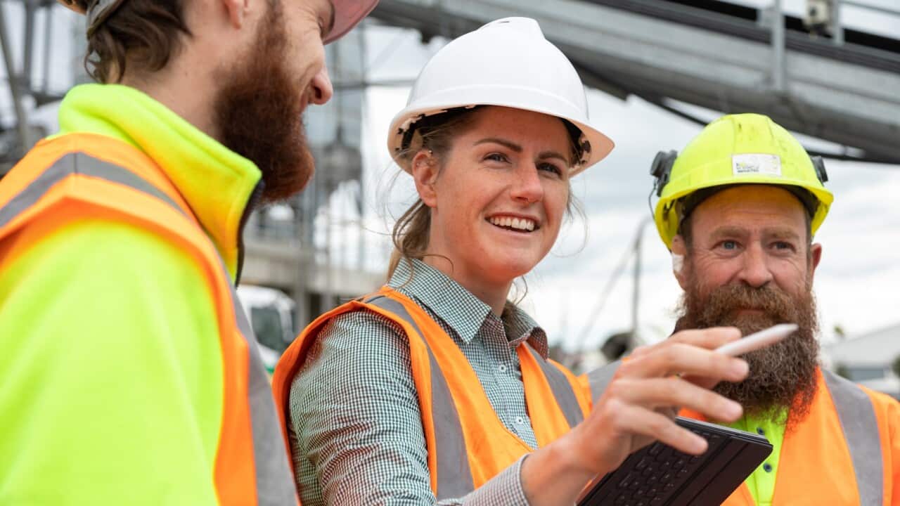 A woman in a leadership role talks to male colleagues on a constuction site