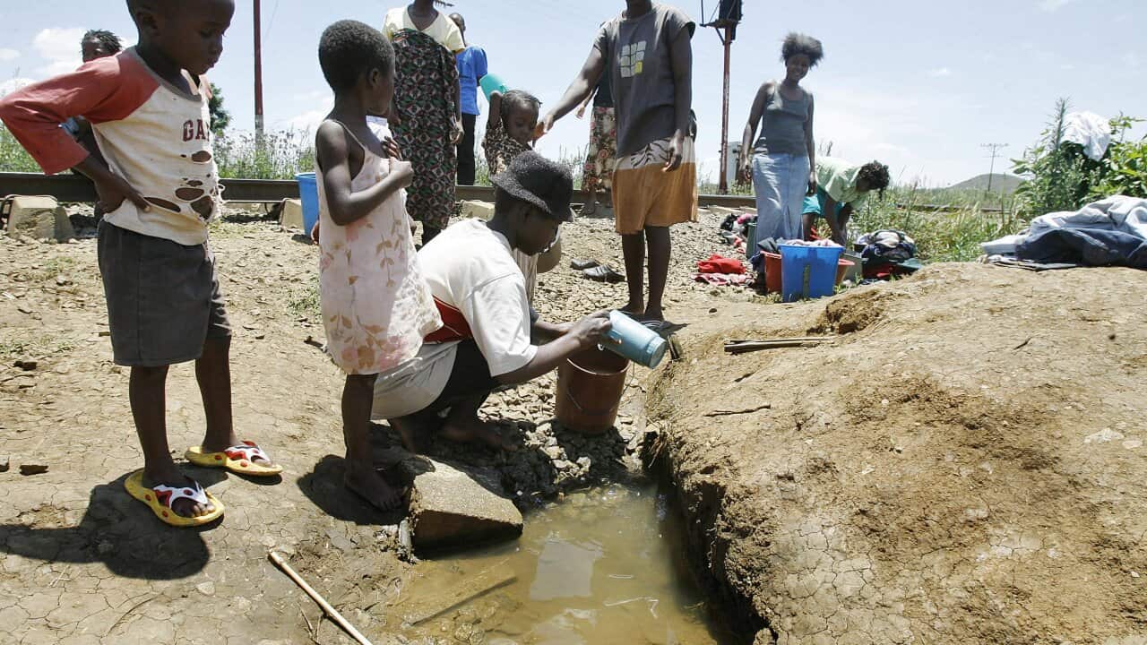 Zimbabwean women and children fetch water from an unprotected well in Harare AAP.jpg