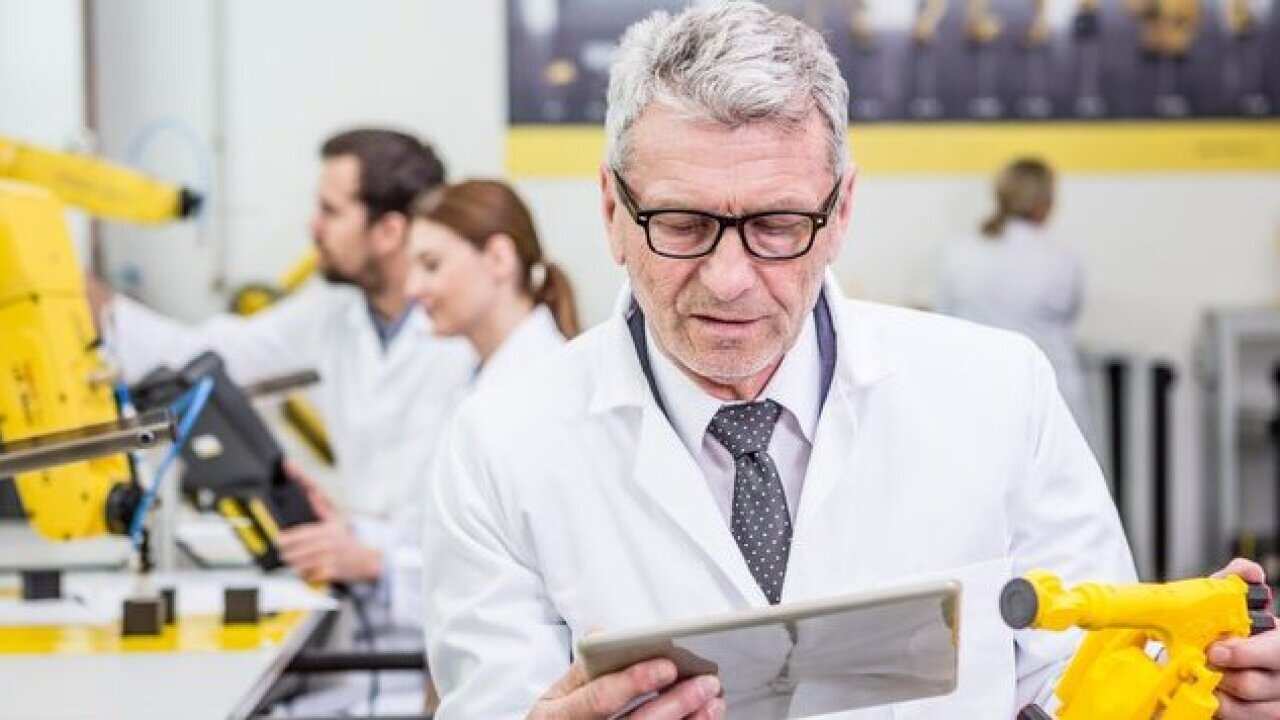 Engineer holding tablet and model of an industrial robot