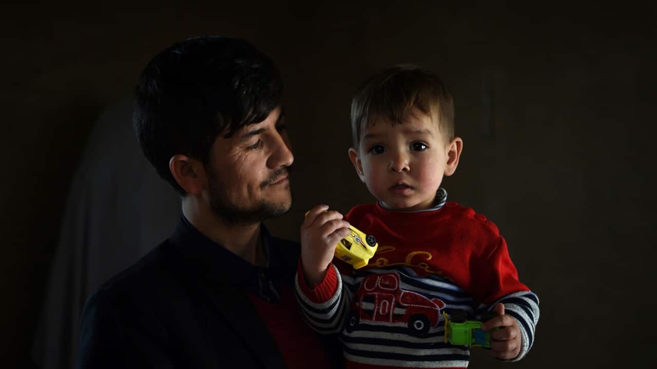 Afghan father Sayed Assadullah Pooya, 28, posing for a photograph with his son Donald Trump
