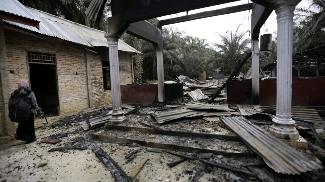 An Acehnese woman walks next to a burned Church in Aceh Singkil, Indonesia, 14 October 2015.