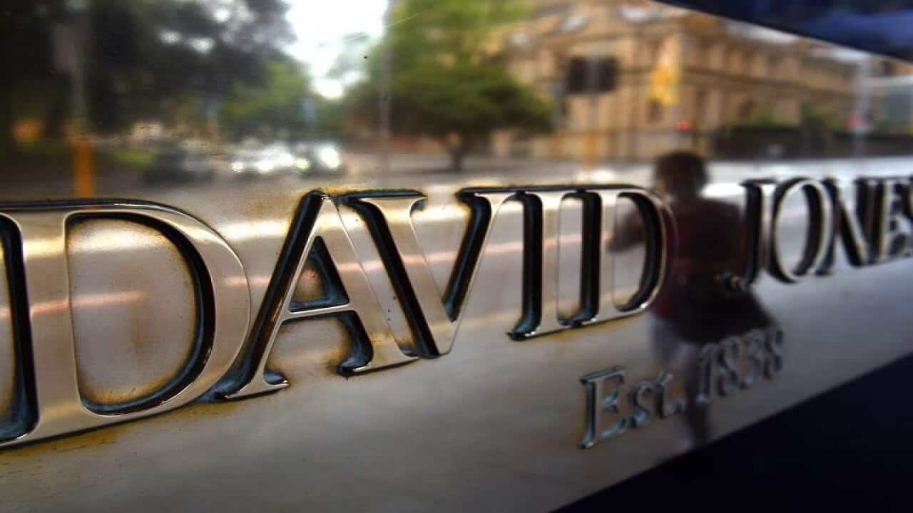 A pedestrian walk past a sign outside a David Jones department store.