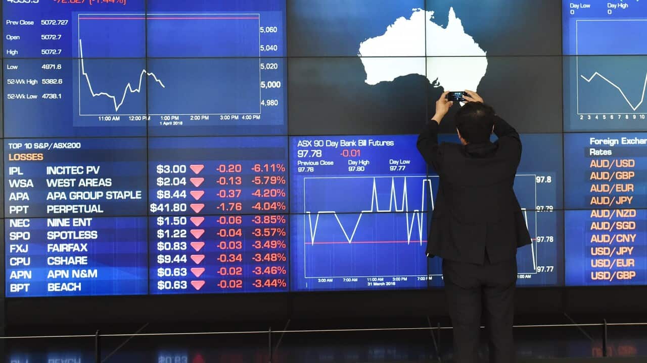 A tourist takes photos of the Australian Stock Exchange  indicator board in Sydney (AAP)