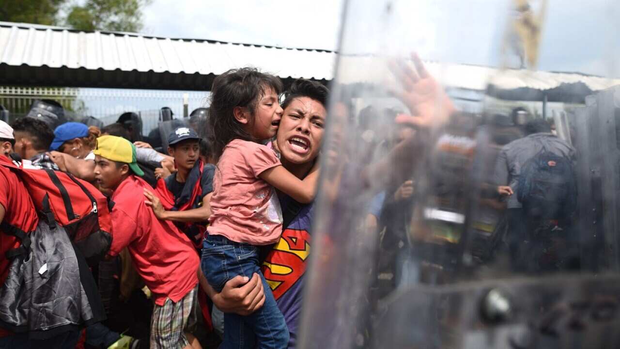 A Honduran migrant Mexican confronts police at the border crossing between Guatemala and Mexico.