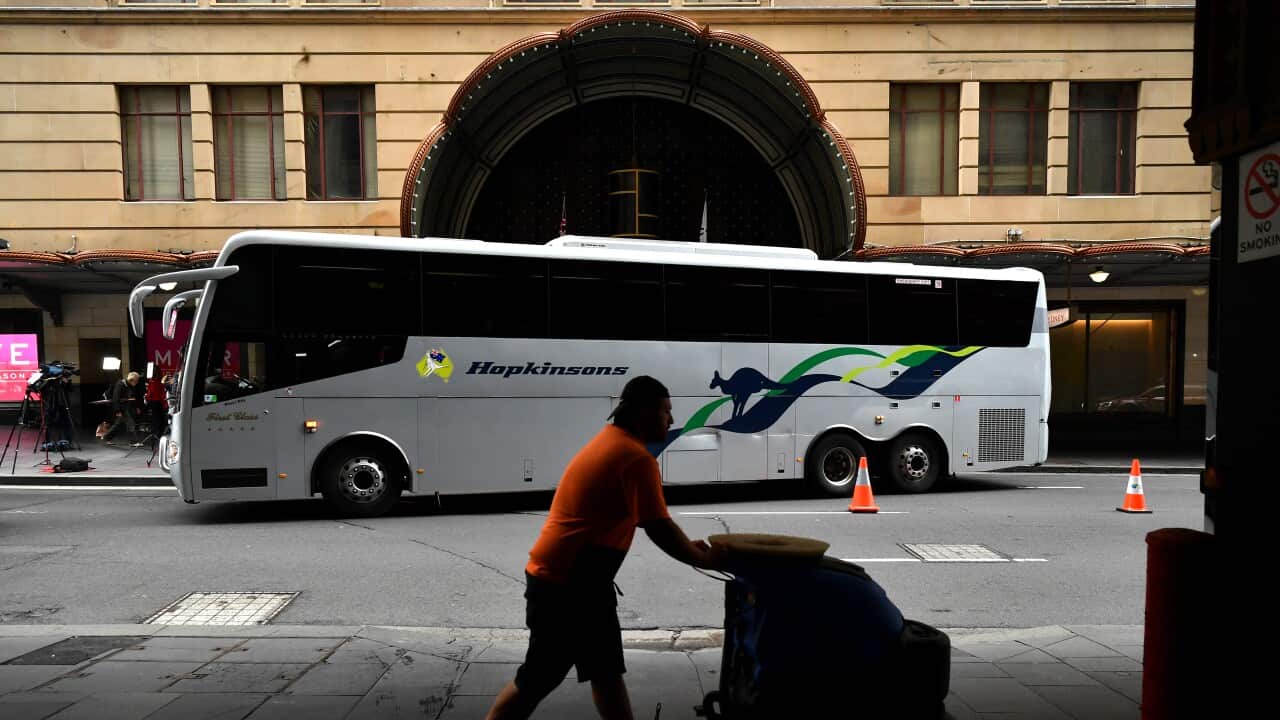 A bus carrying overseas returned travellers departs a hotal quarantine location, the Swissotel in Sydney.