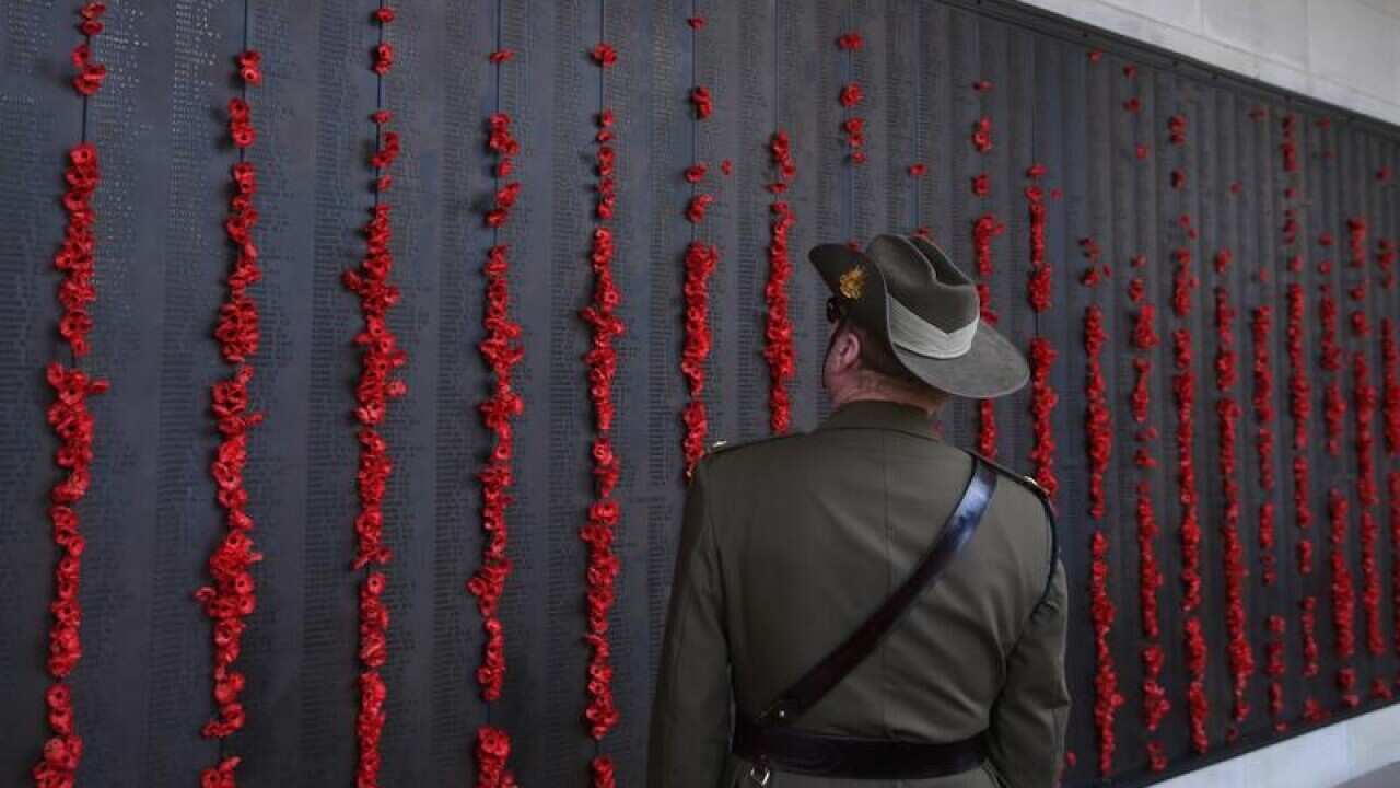 A man in uniform walks along the Roll of Honour