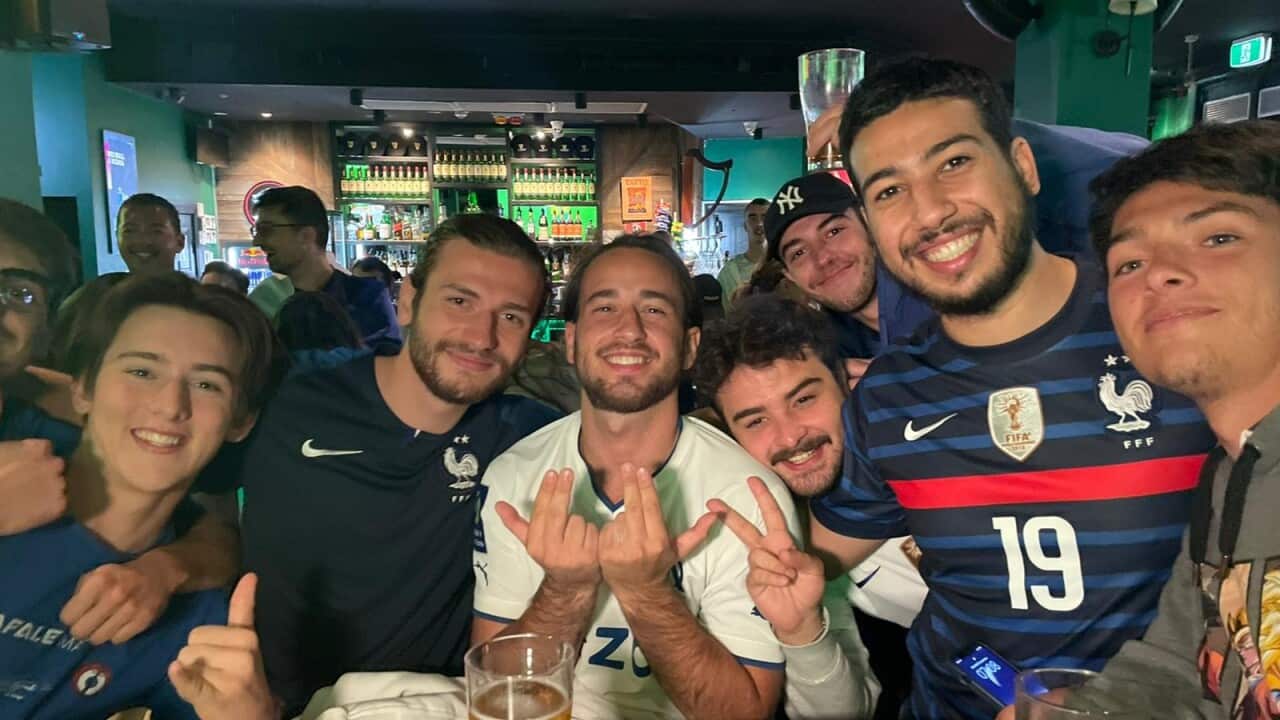 Group of people crowded around a table in a bar