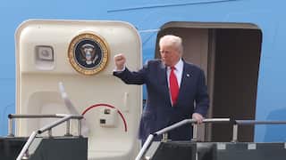 Man in suit holds up fist while boarding plane