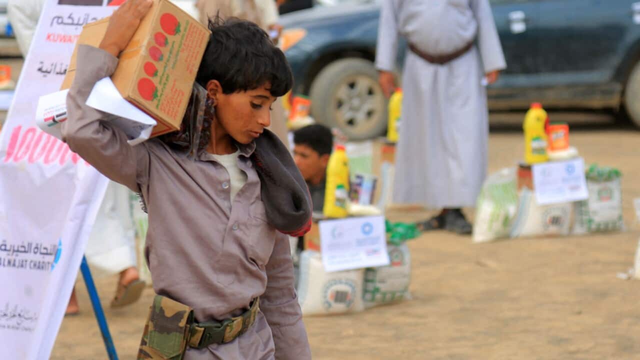 A boy carries humanitarian aid provided by a Kuwaiti charitable organisation