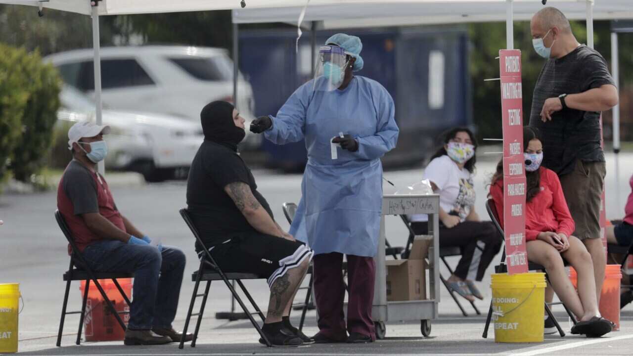 A Florida health care worker administers COVID-19 tests