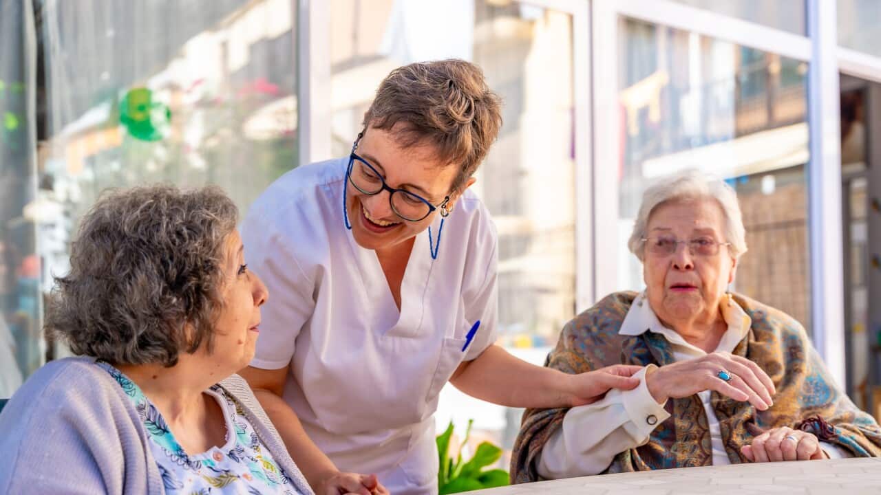 Nurse visiting seniors sitting in the garden of a geriatric