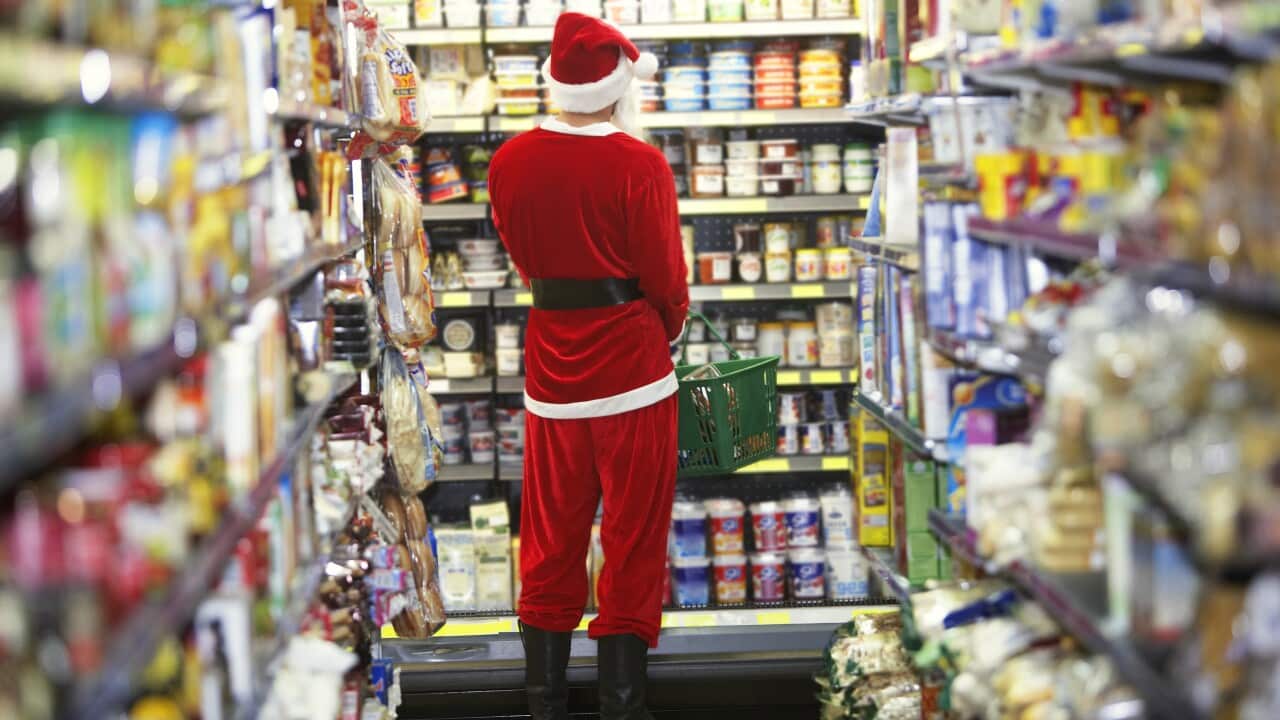 Man dressed as Santa Claus standing in supermarket, rear view