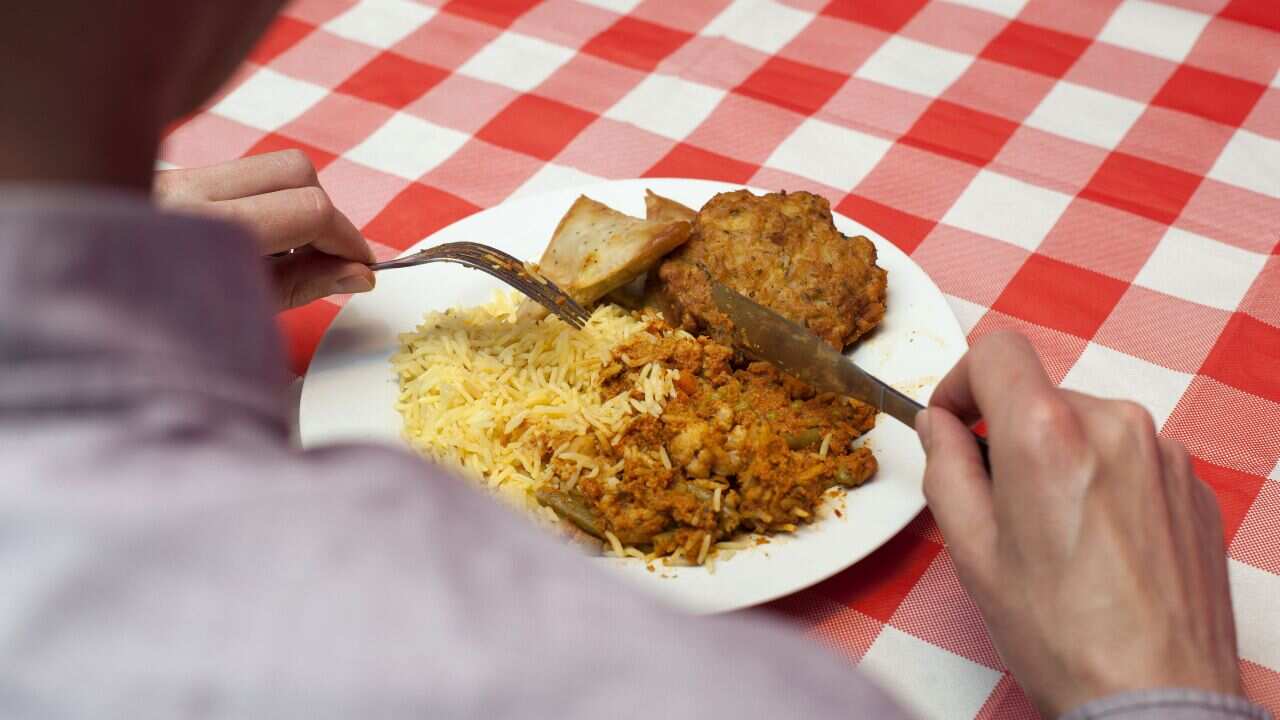 A dish of vegetable tikka masala, rice, samosas and an onion bhaji.