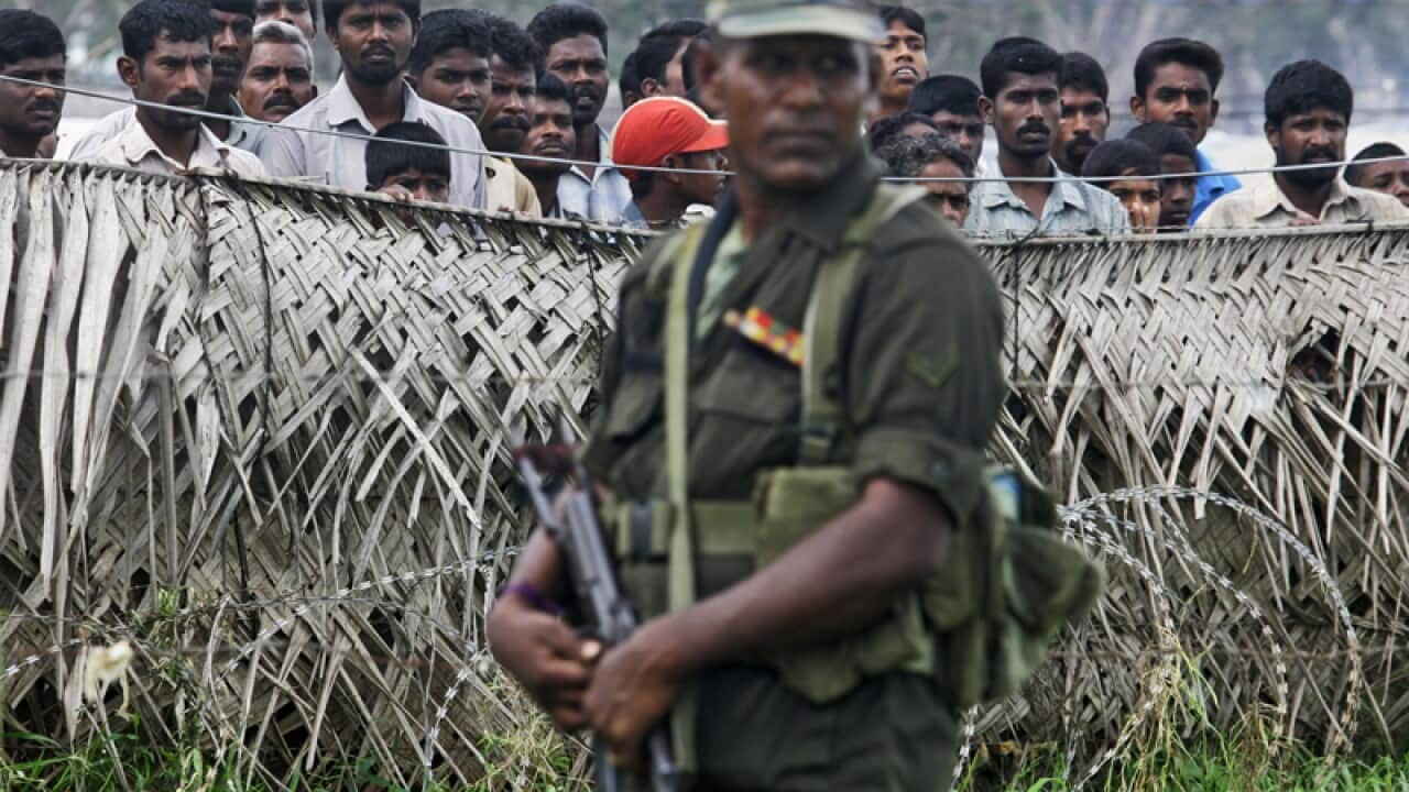 A Sri Lankan soldier next to internally displaced civilians, Sri Lanka