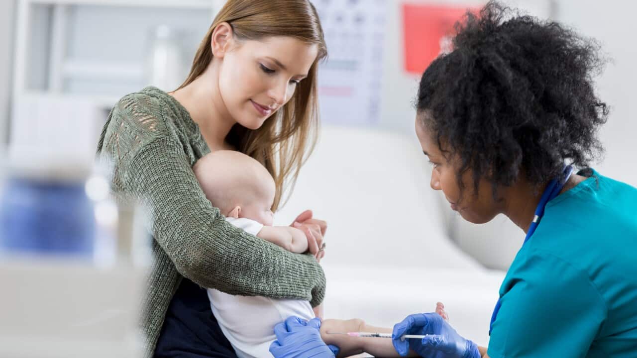 A pediatric nurse gives an infant an immunisation.