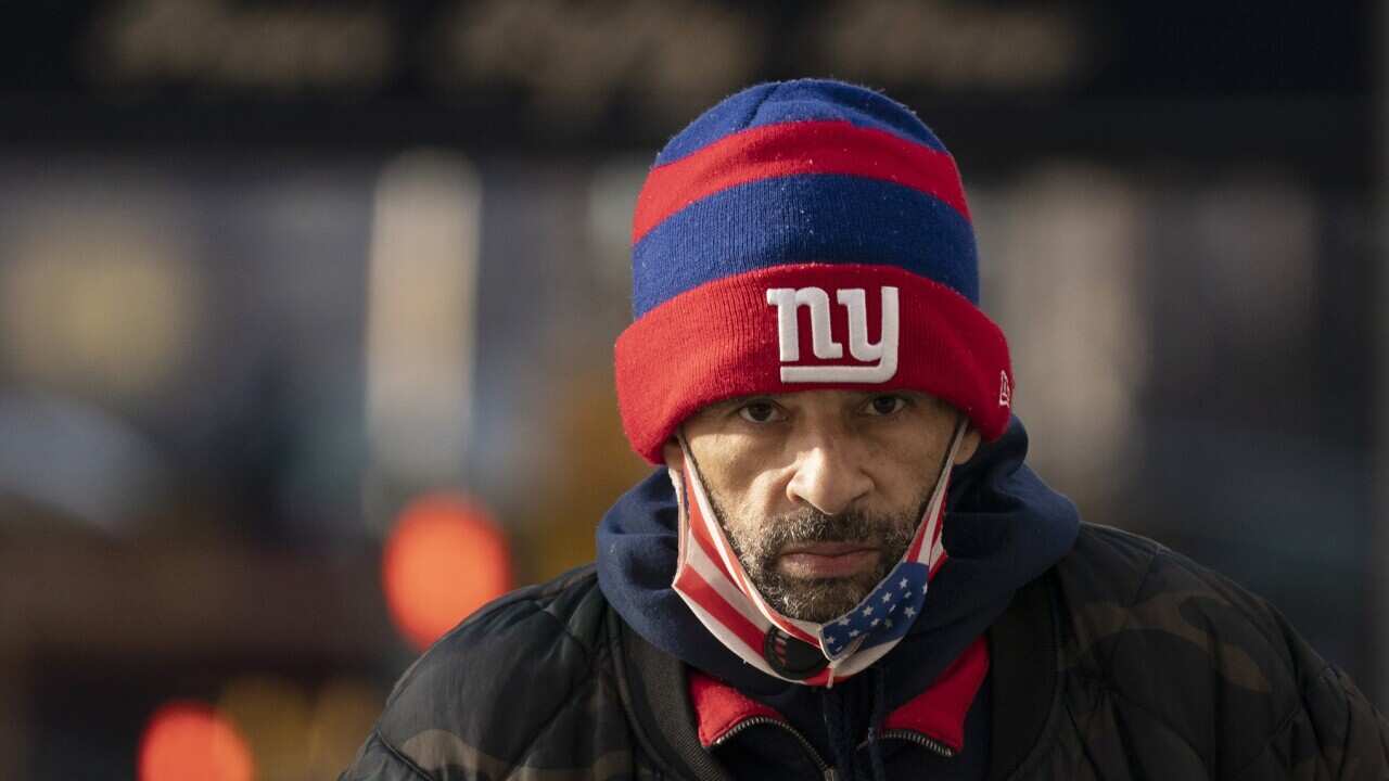 A man wearing a face mask walks on the street, Tuesday, Jan. 19, 2021, in New York. The city will run out of first doses of COVID-19 vaccine sometime Thursday without fresh supplies, Mayor Bill de Blasio said Tuesday.(AP Photo/Mark Lennihan)