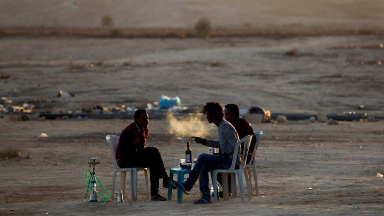 Eritrean refugees smoke water pipes and drink at a makeshift cafe
