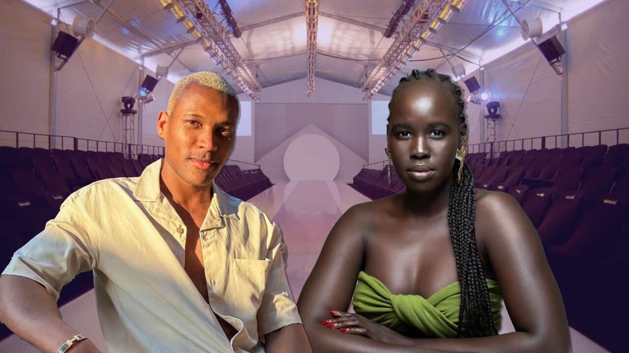 A smiling man in a linen shirt with a relaxed pose, next to a solemn woman in a green strapless dress. An empty runway behind