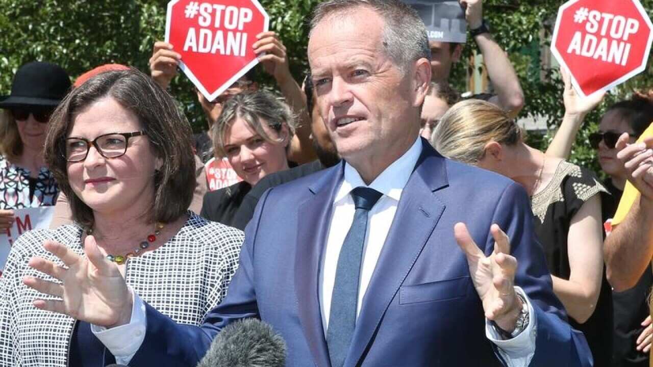 Opposition Leader Bill Shorten speaks with Adani protester behind him.