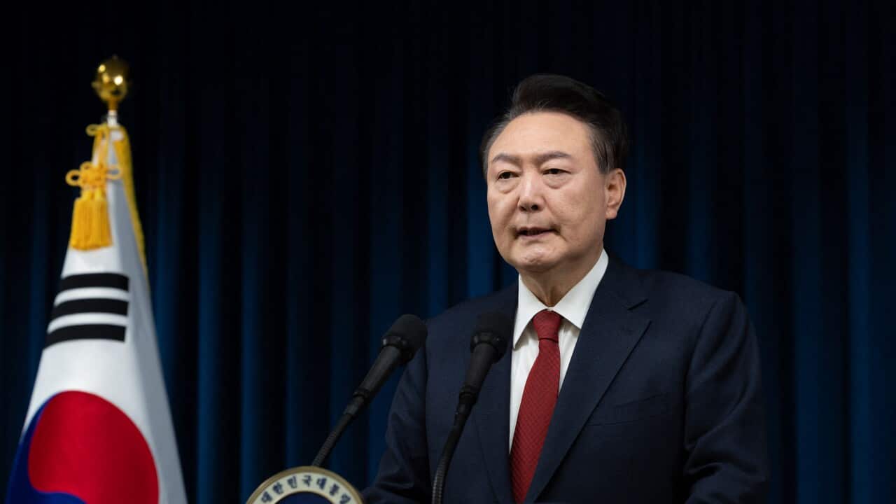 A man wearing a suit and a tie speaks at a press conference with the South Korean flag to his right