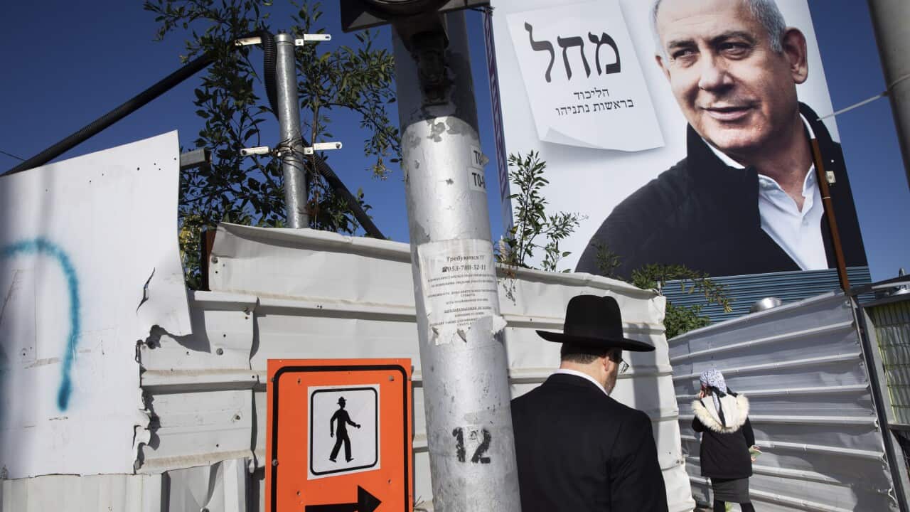 People walk next to election campaign billboards for Benjamin Netanyahu's Likud Party in Bnei Brak, Israel, Sunday, 1 March, 2020.