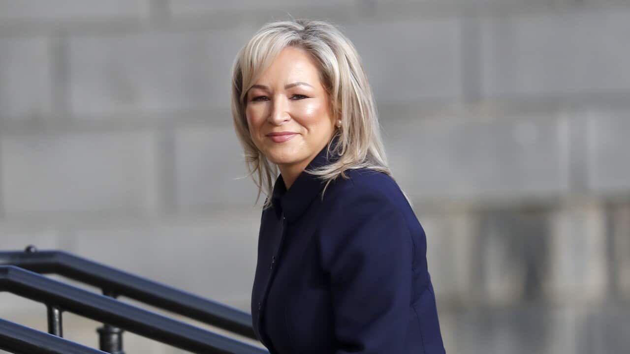 A blonde woman in a navy blazer walking up stairs