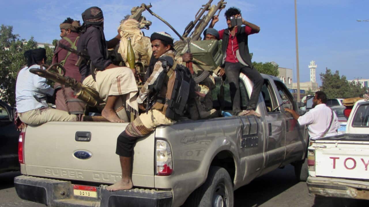 Militiamen ride on an army vehicle while patrolling a street in Aden.