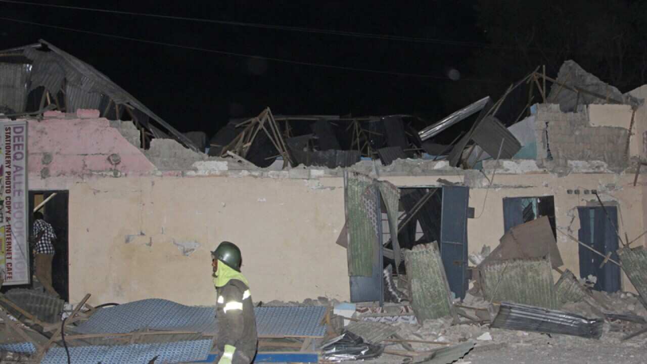 A fireman walks past houses destroyed in a suicide car bomb, Somalia