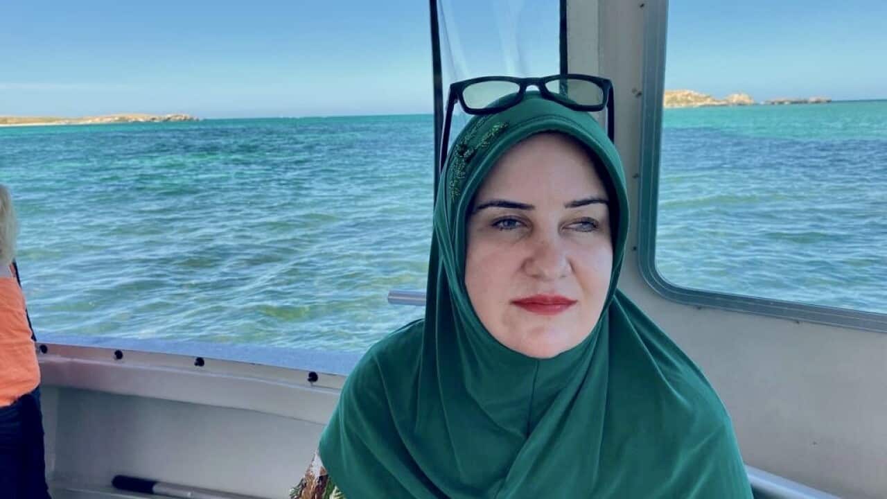 A visually impaired woman in a green head scarf on the boat