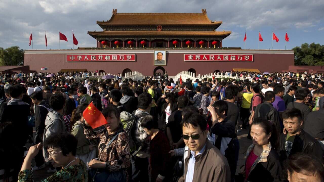 Tourists walk in front of Tiananmen Gate on the National Day