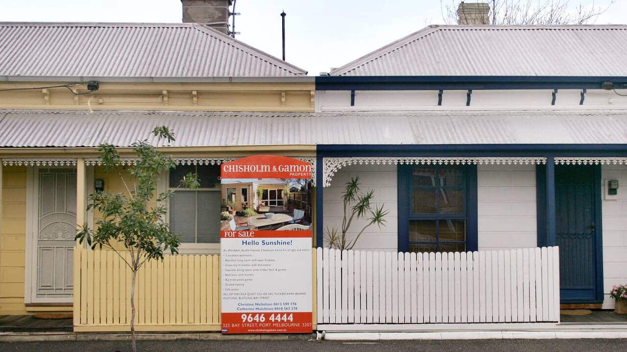 A for sale sign between two small houses