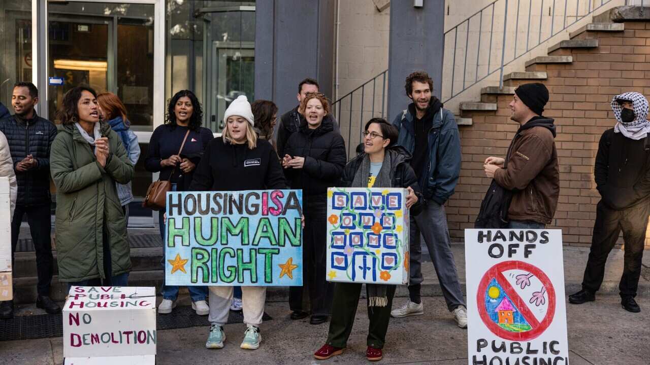 People hold up signs opposing the demolition of the towers.