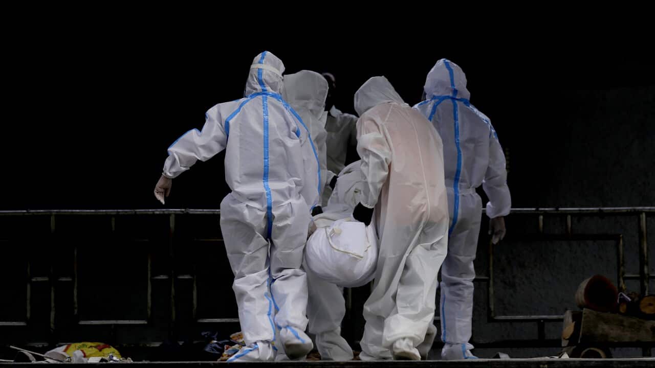 Relatives dressed in protective suits carry a body of their family member who died of coronavirus in India. 