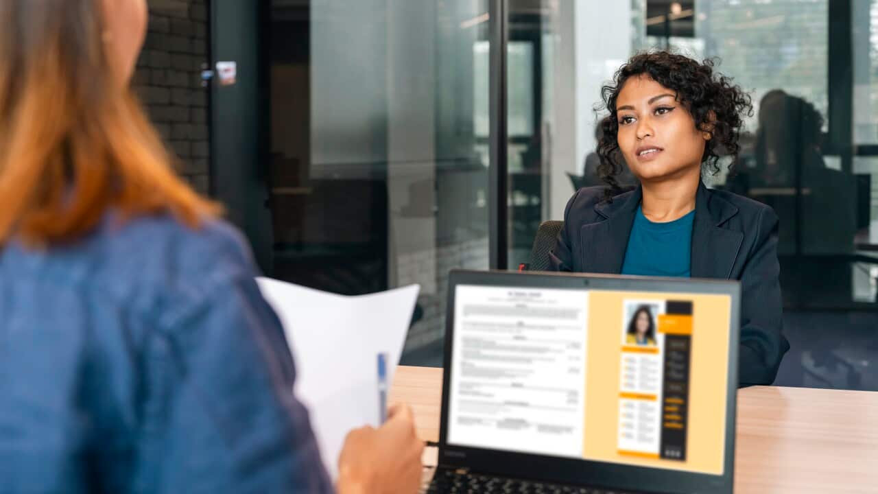 Recruiter holding candidate resume taking job interview at desk.