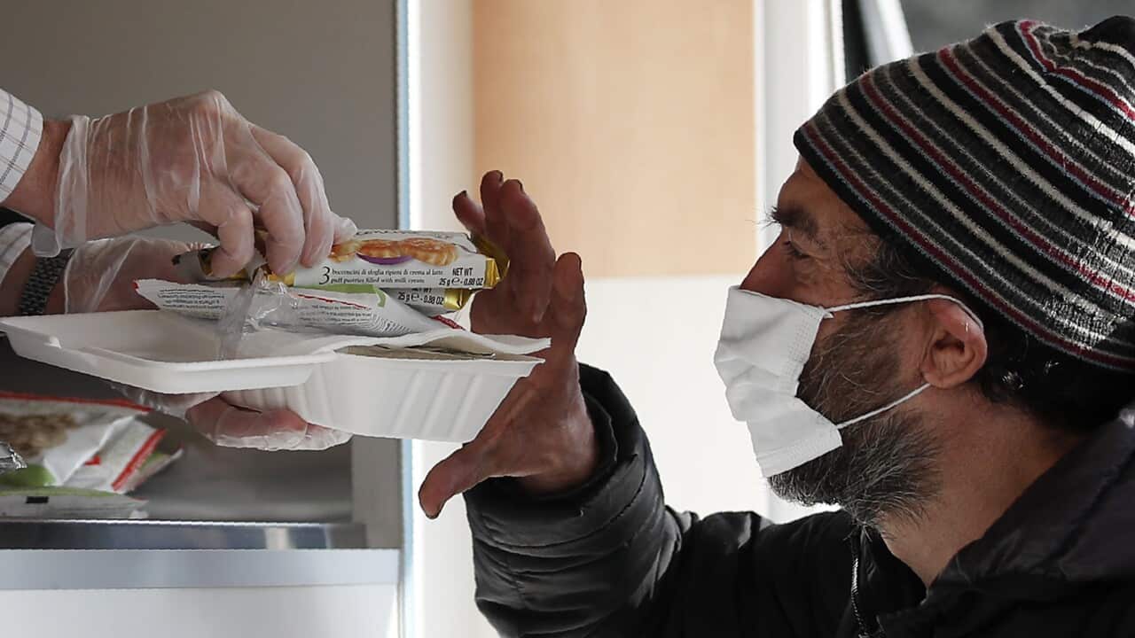A volunteer services a homeless man some food in Italy