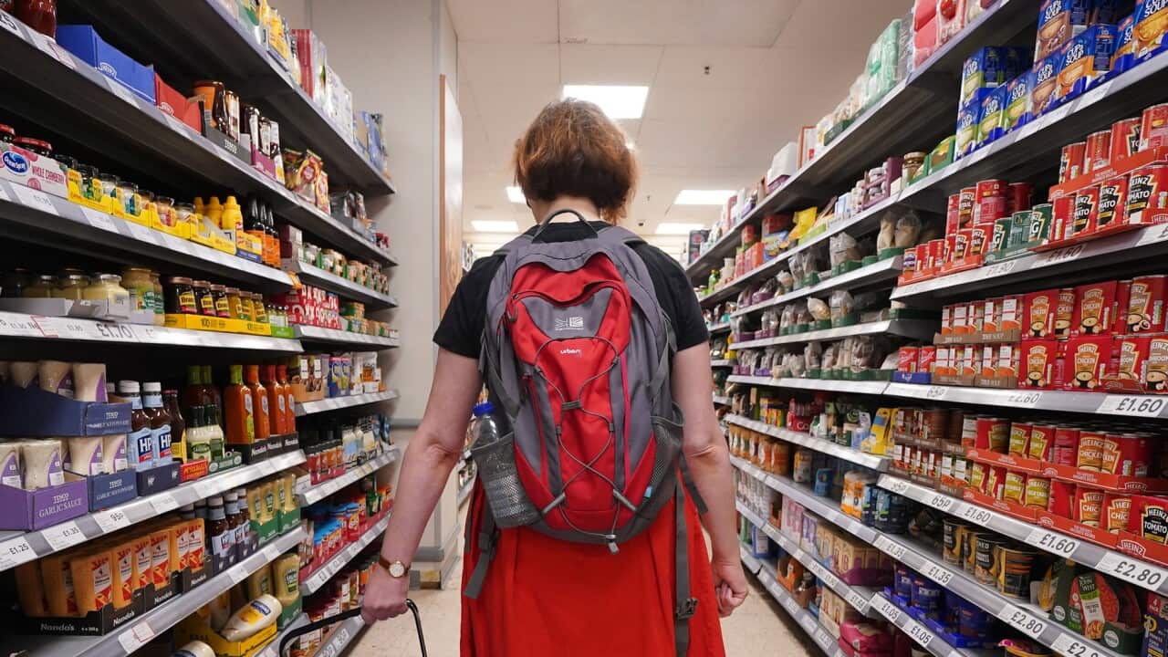 A woman carrying a shopping basket at a grocery store
