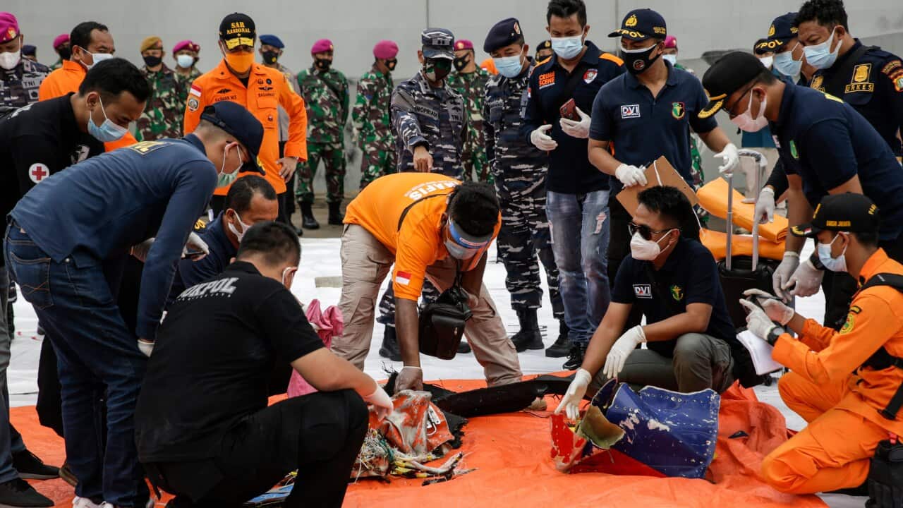 Indonesian rescuers and Disaster Victim Identification police officers sort through the suspected debris of Sriwijaya Air flight SJ182.