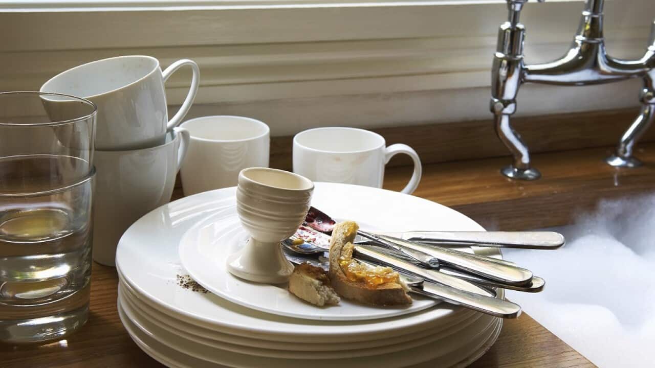 Stack of Dirty Dishes and silverware by Sink