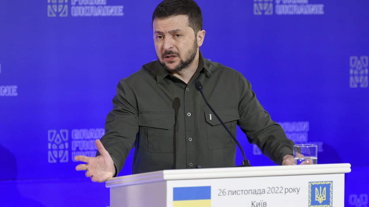 Ukraine's President Voloydmyr Zelenskyy stands at a podium in front of the media