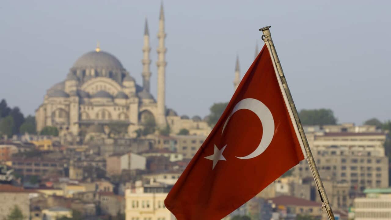 Turkish Flag on back of boat and Mosque on hillside just above.