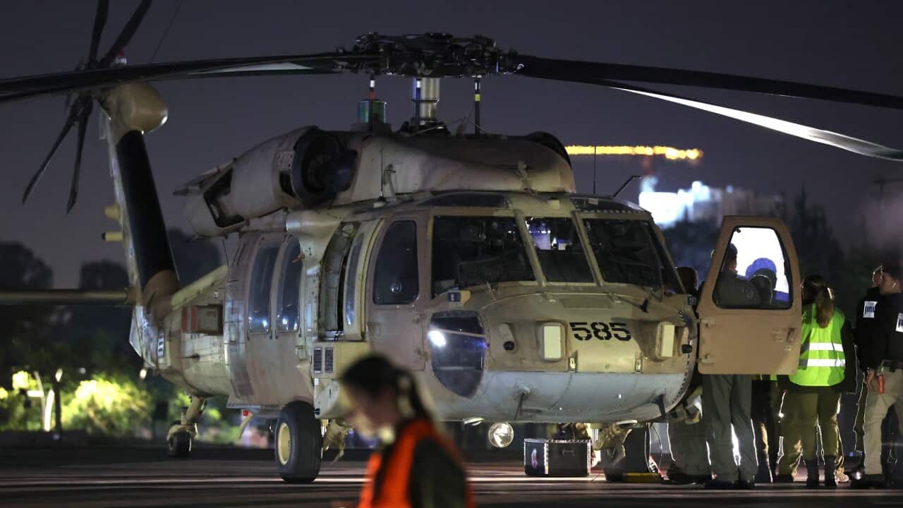 Staff stand near a helicopter on the tarmac.