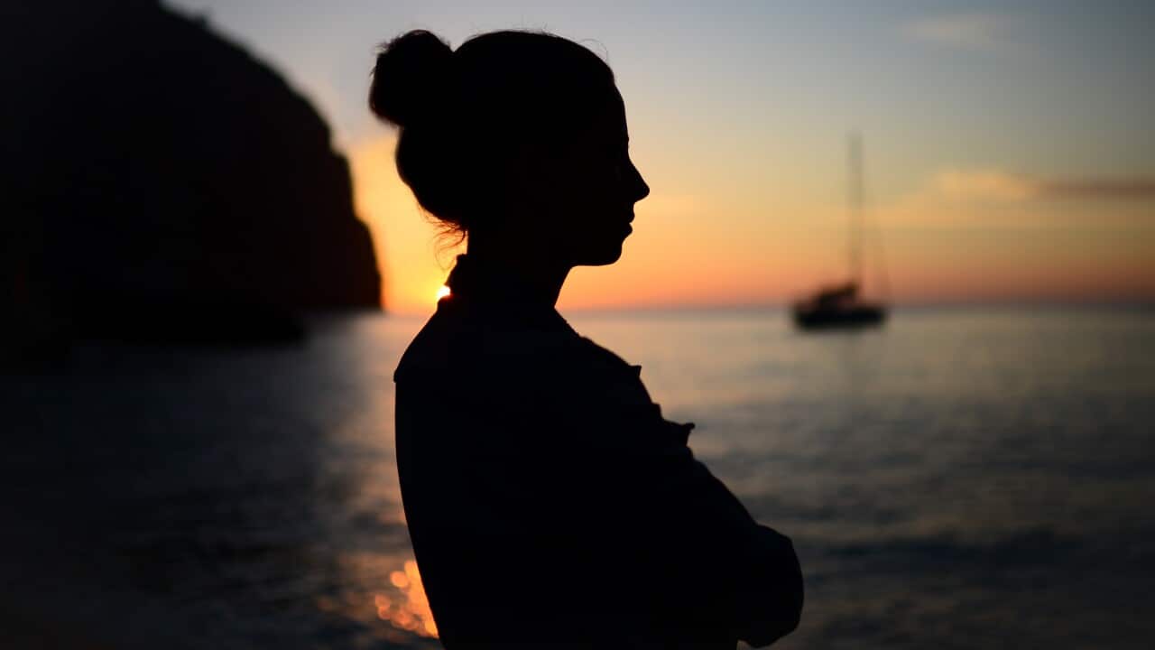 Silhouette of a contemplative young woman enjoying a beautiful sunset