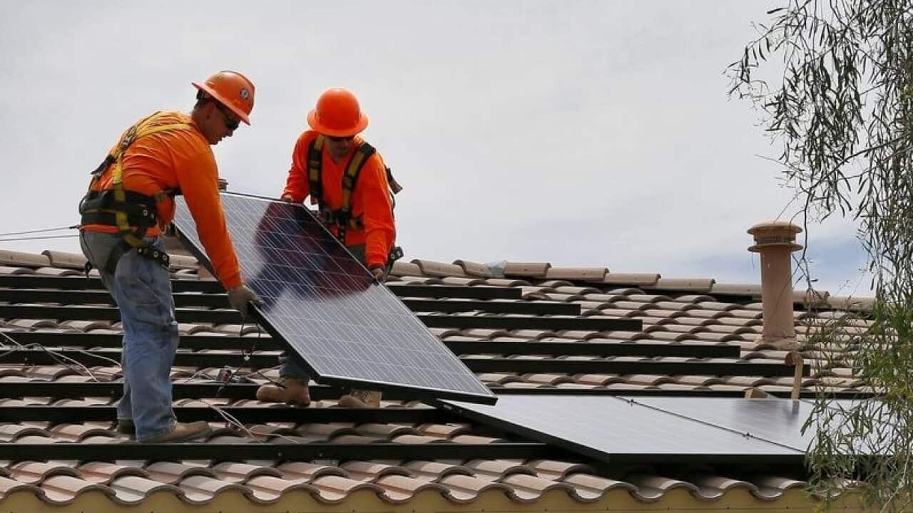 Electricians install a solar panel