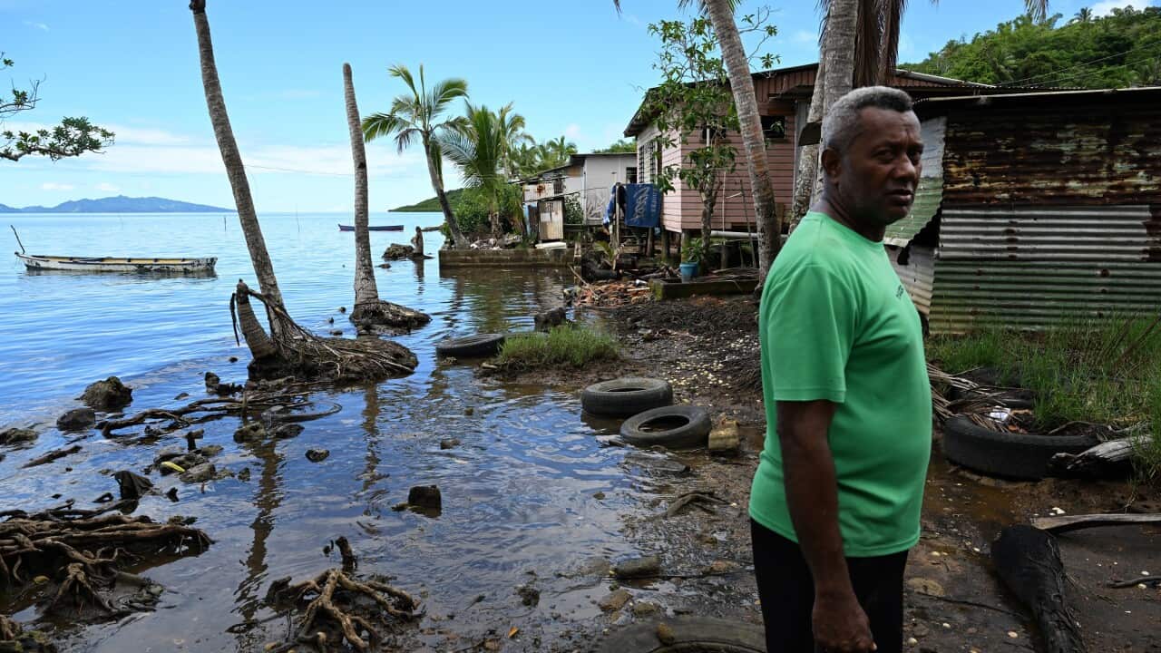 Tuiverata stands in front of houses impacted by rising sea levels in the village of Veivatuloa, Fiji.