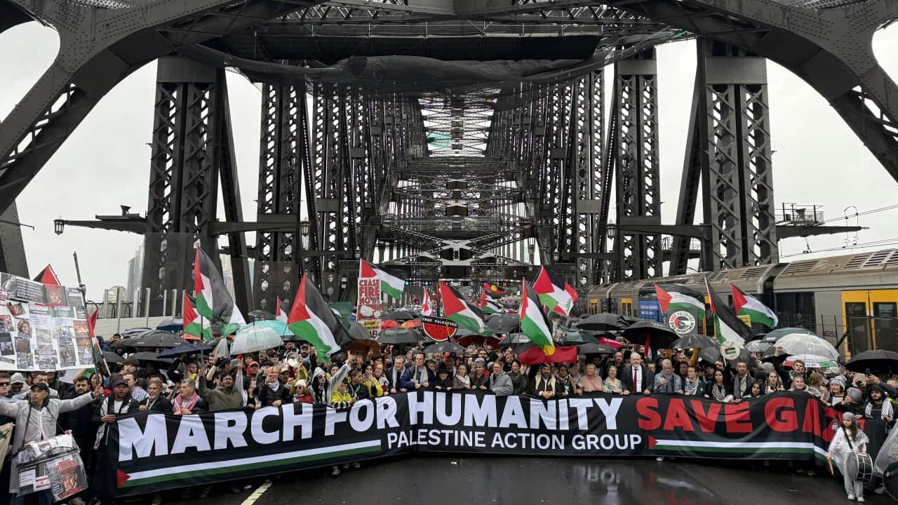 A large group of protesters crosses the Sydney Harbour Bridge carrying a banner reading "March for Humanity. Save Gaza."