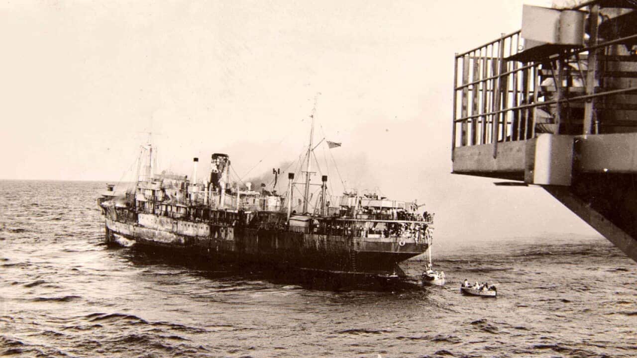 The SS Empire Patrol burning as seen from the bow of HMS Trouncer. Note the rescue boats in the water