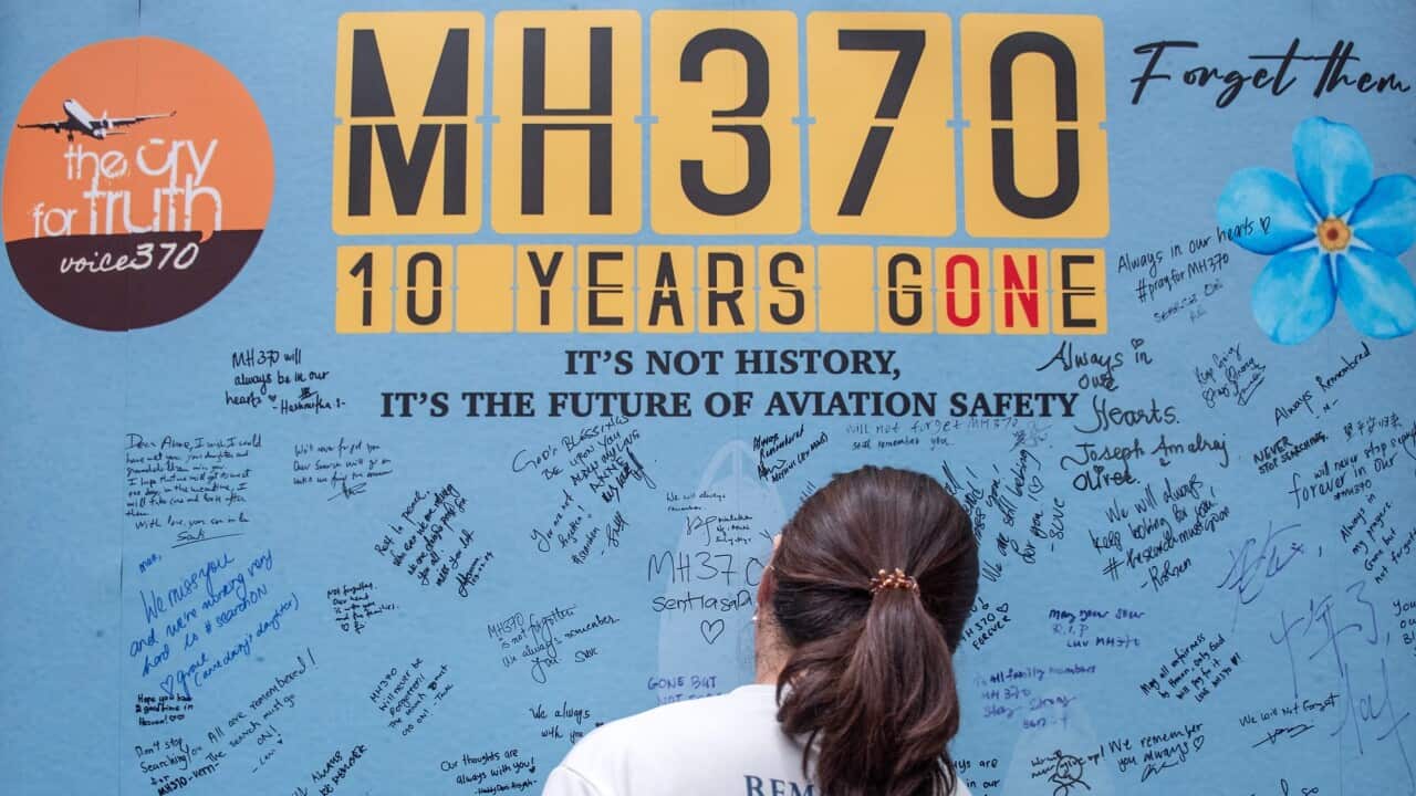 A female is seen writing a tribute message on a mural.