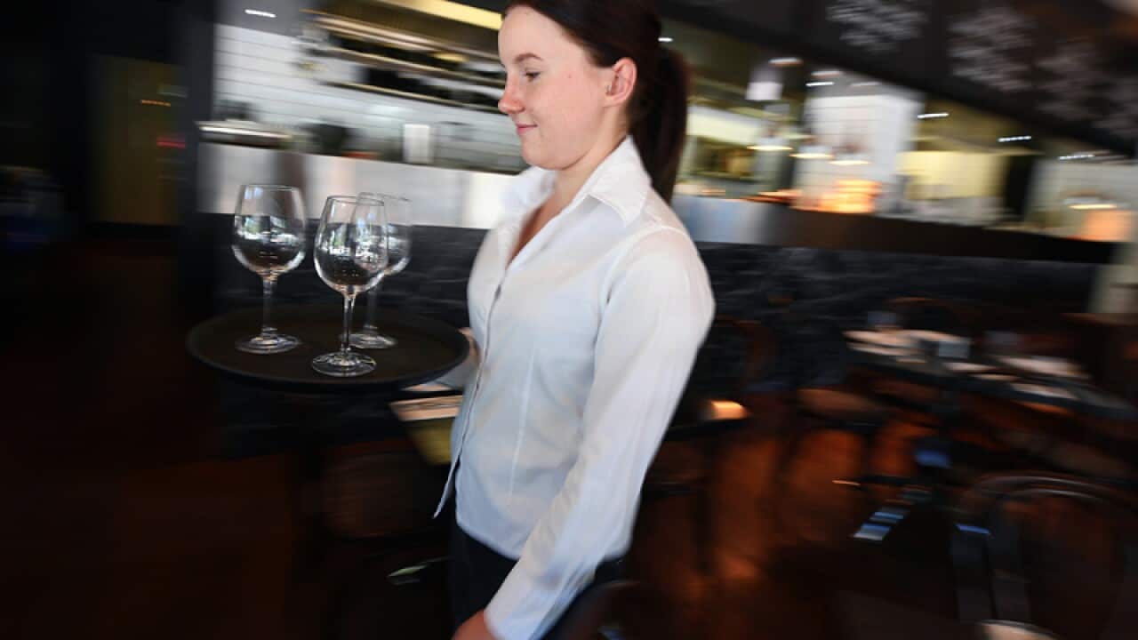 A waitress is seen setting up a table at a restaurant in Canberra