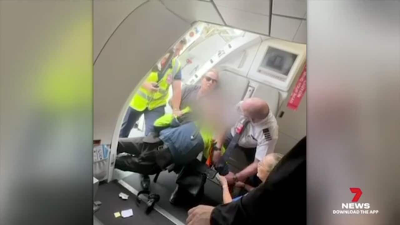 A blurred image of a person being held down by a group of people